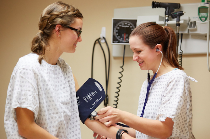 Students practice checking blood pressure during a class.