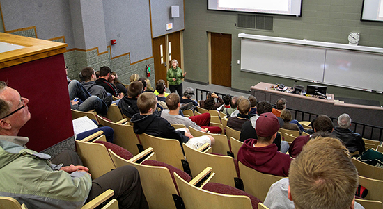 Image of M.Darby Dyar presenting in front of a full Cowley Hall auditorium.
