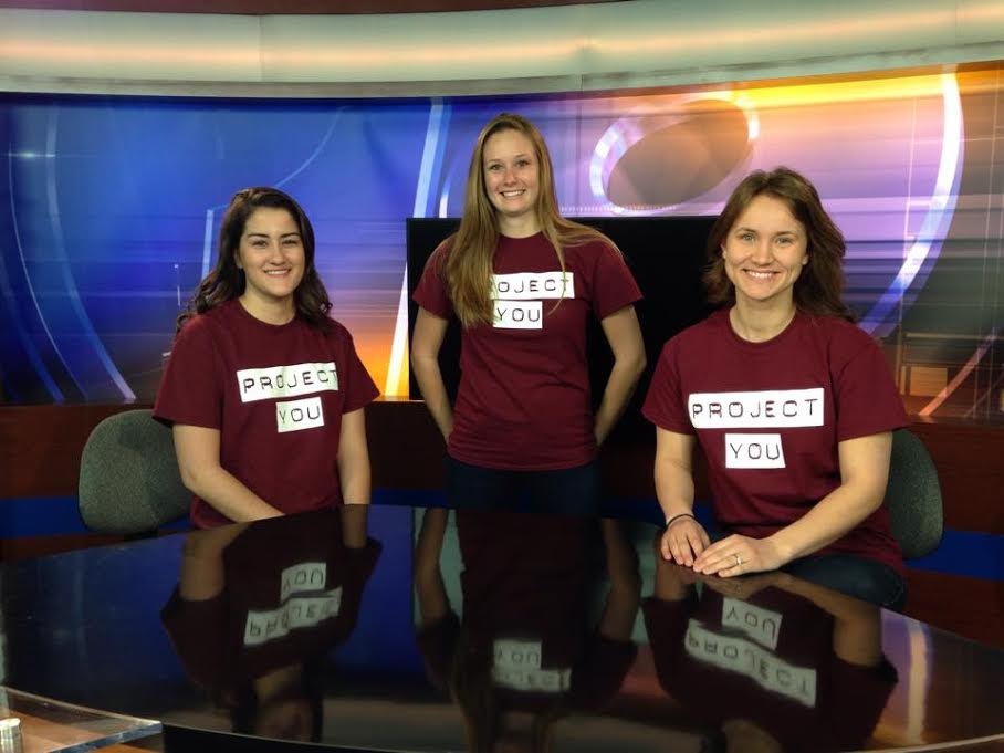 Image of students sitting and standing with studio lights in the background. 