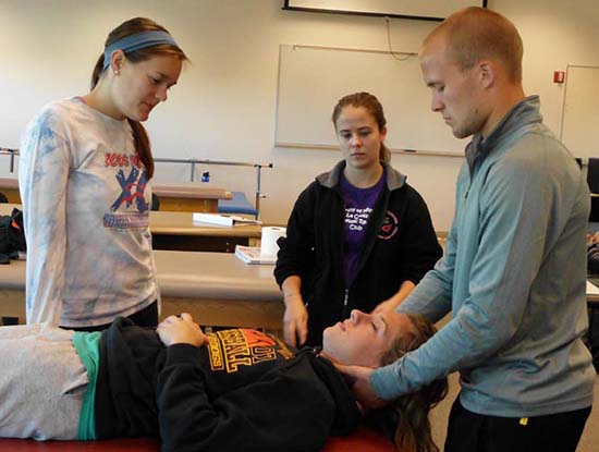 PT students practicing a technique where one student lays at a table while another student has hands near the neck.