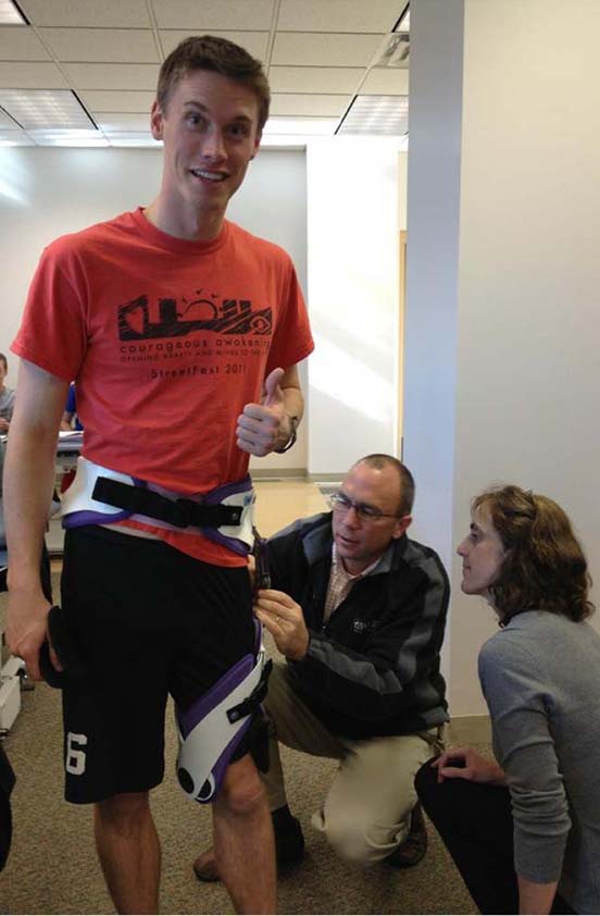 PT student wears leg brace while faculty members fascine it.