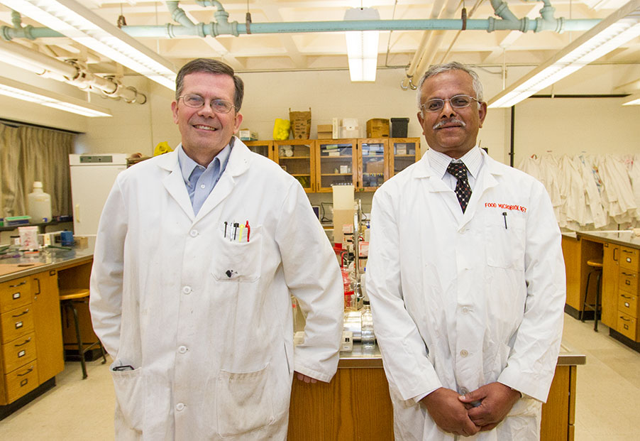 Image of Microbiology Professors Mike Winfrey and S.N. Rajagopal standing together in lab coats. 
