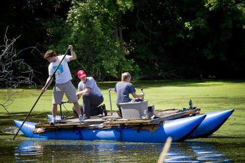 Students and faculty on a raft at the La Crosse River Marsh collecting soil samples