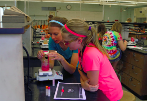 Tanya Cordes assists a student using chemistry to create lip gloss as part of the workshop :Lovely Lips Laboratory."