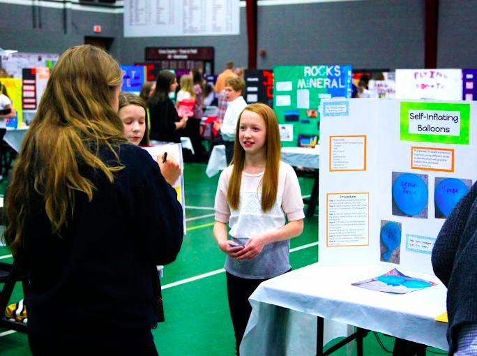 Image of a student presenting at the Science and Math Expo near a poster