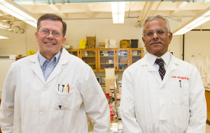 Image of Mike Winfrey and S.N. Rajagopal standing in lab coats in a microbiology lab room.