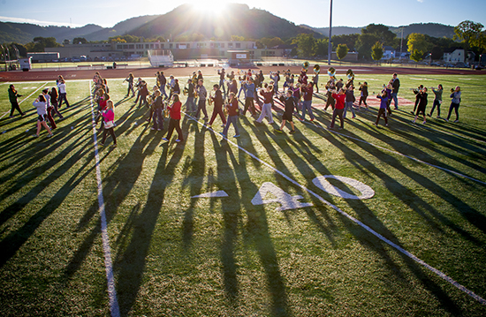 Image of students marching on the football field with Grandad Bluff in the background. 