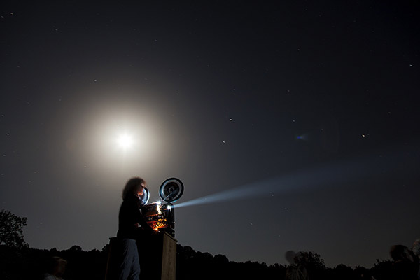 Image of woman at night, operating a projector.