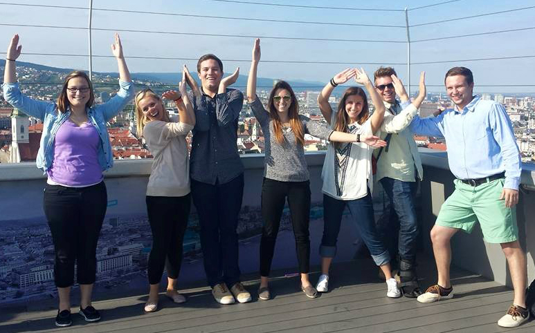 Image of students spelling letters UW LAX with their arms at the top of the lookout tower. 