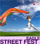 Streetfest Woman jumping with colorful sash against blue sky.