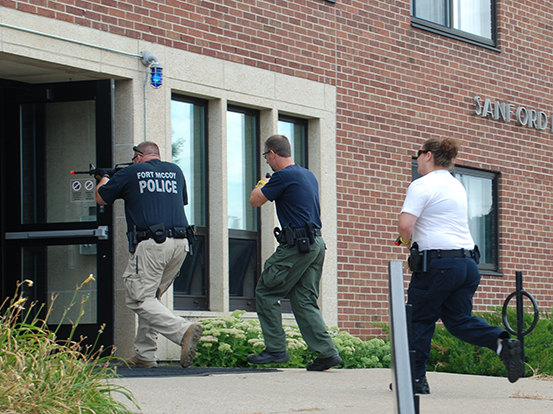 Officers entering Sanford Hall door with equipment.
