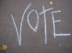Word vote chalked on sidewalk. 