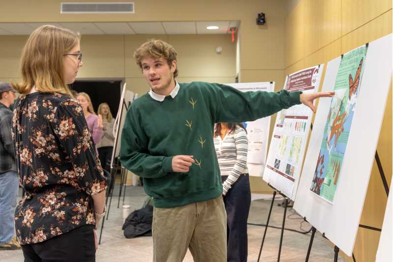 At right, Junior Finn Patenaude, a geography major with GIS concentration, presents maps on optimal sites for wildlife crossings and the mass migration of monarch butterflies during UWL’s Geography & Environmental Science Department reverse career fair where students shared their projects with employers. The GIS classes here at UWL give us the tools that both unlock our imagination and allows it to run wild. Showing our creative side in addition to our academic and technical skills allows us as students to share what makes us special and unique with potential employers, he says.