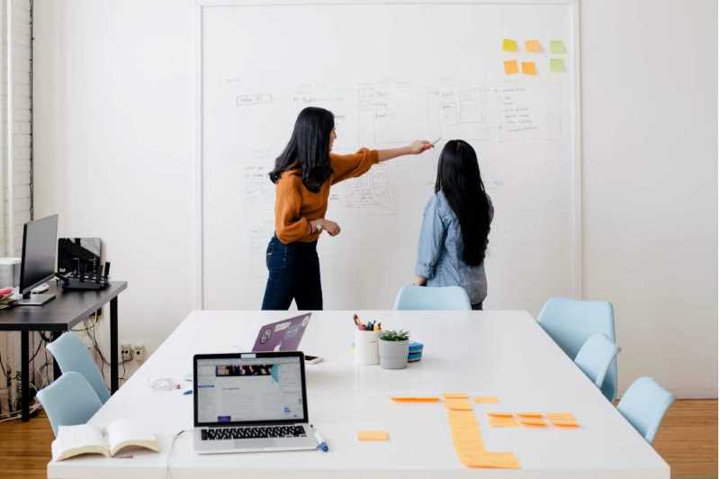 Two people at a whiteboard. One pointing at a diagram.