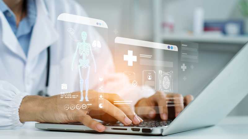 Healthcare professional using a laptop with digital medical data and AI-generated health information displayed on screen.