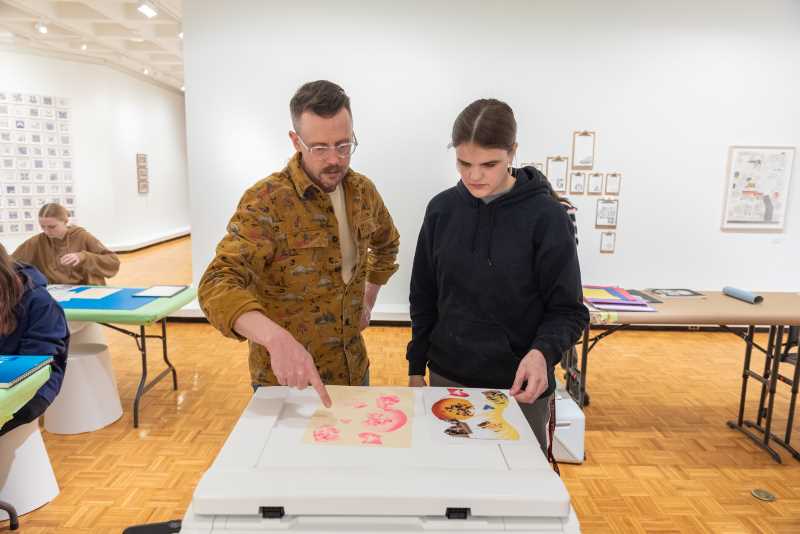 One highlight was a Risograph workshop held in the gallery itself, where students created pieces surrounded by Head’s exhibition. Using writing and drawing prompts, they developed paper collages that were later Risograph-printed and hand-bound into a collaborative anthology. Here Visiting Artist Travis Head examines Risograph prints with a student workshop participant.