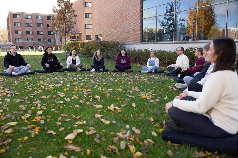 A UWL mindfulness classes practices meditation outdoors on the UWL campus greens.