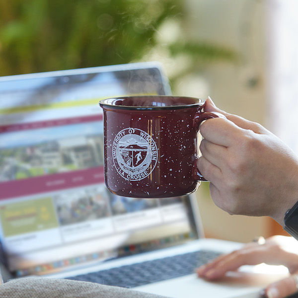 A student taking online classes and holding a UWL coffee mug