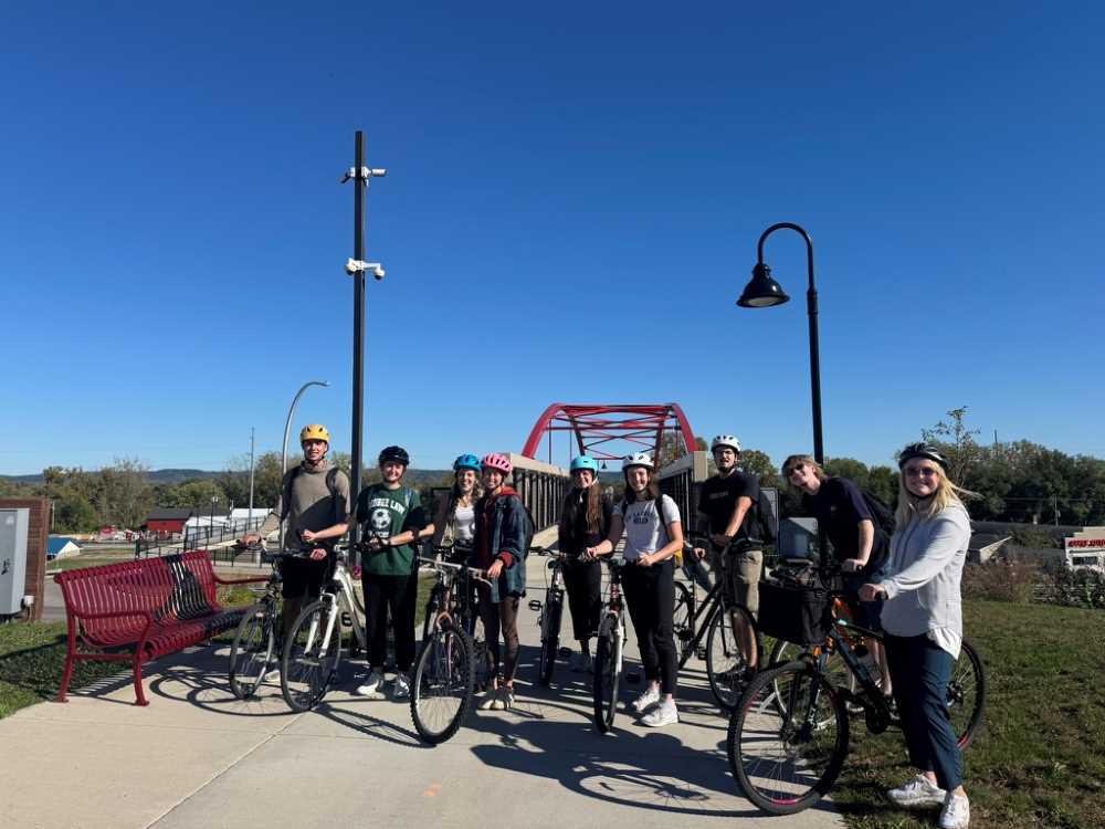 Students biking by the Mississippi River and bridge.