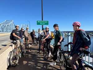 Students biking by the Mississippi River and bridge