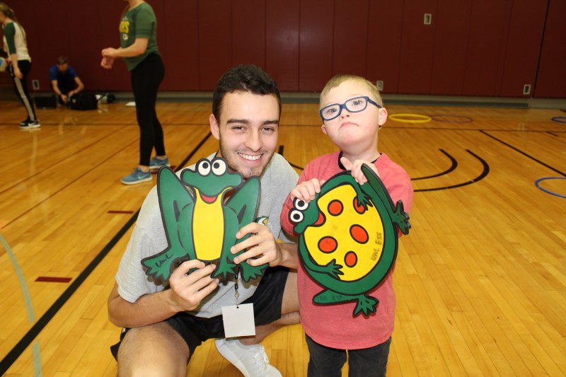 An Adapted Physical Education teaching minor plays with a boy with a disability.