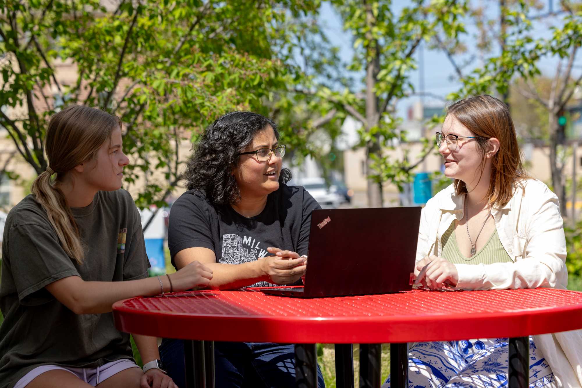 Students and a professor working outside at a computer