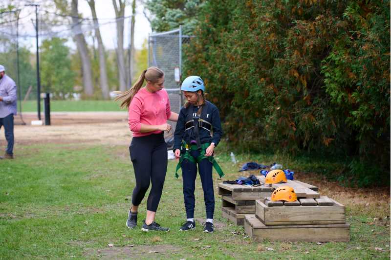 Grad student and youth preparing for ropes course