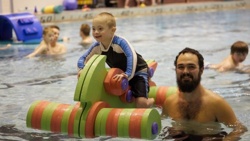 Boy riding pool toy in the pool.