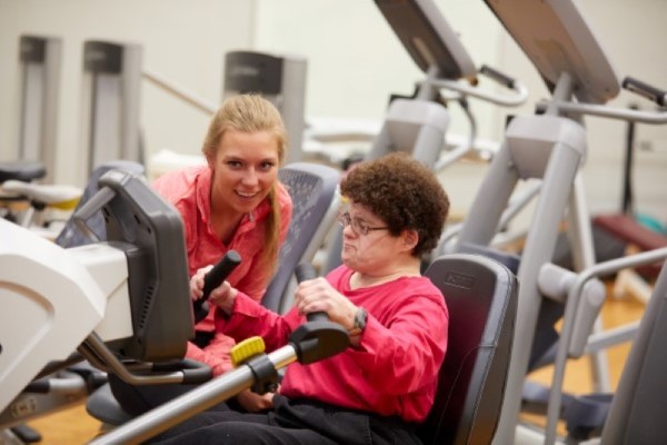 Woman with a disability works out with two student coaches.