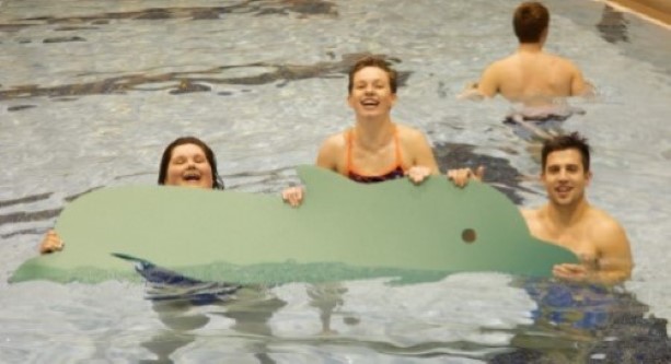 University student volunteers and children have fun floating in the pool during Children's Motor Development.