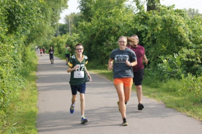 Young man runs the Myrick Mile with his mentors.