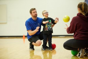 Child throws ball with graduate student help