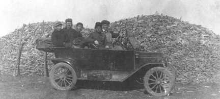 Corn heap behind the car, unknown men.