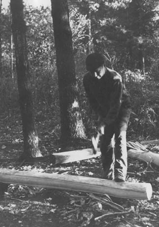 Martin Lowe pounding an ash tree log with the flat end of an axe before strips can be pulled off, thinned, and used as basketry material.
