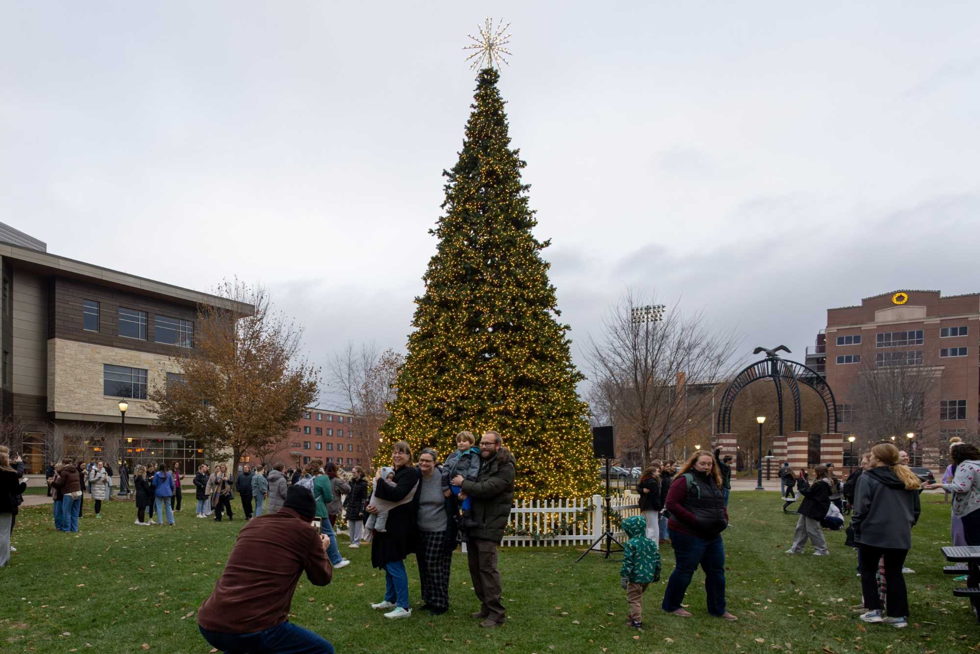 A family taking a picture together in front of the tree.