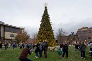 A family taking a picture together in front of the tree.