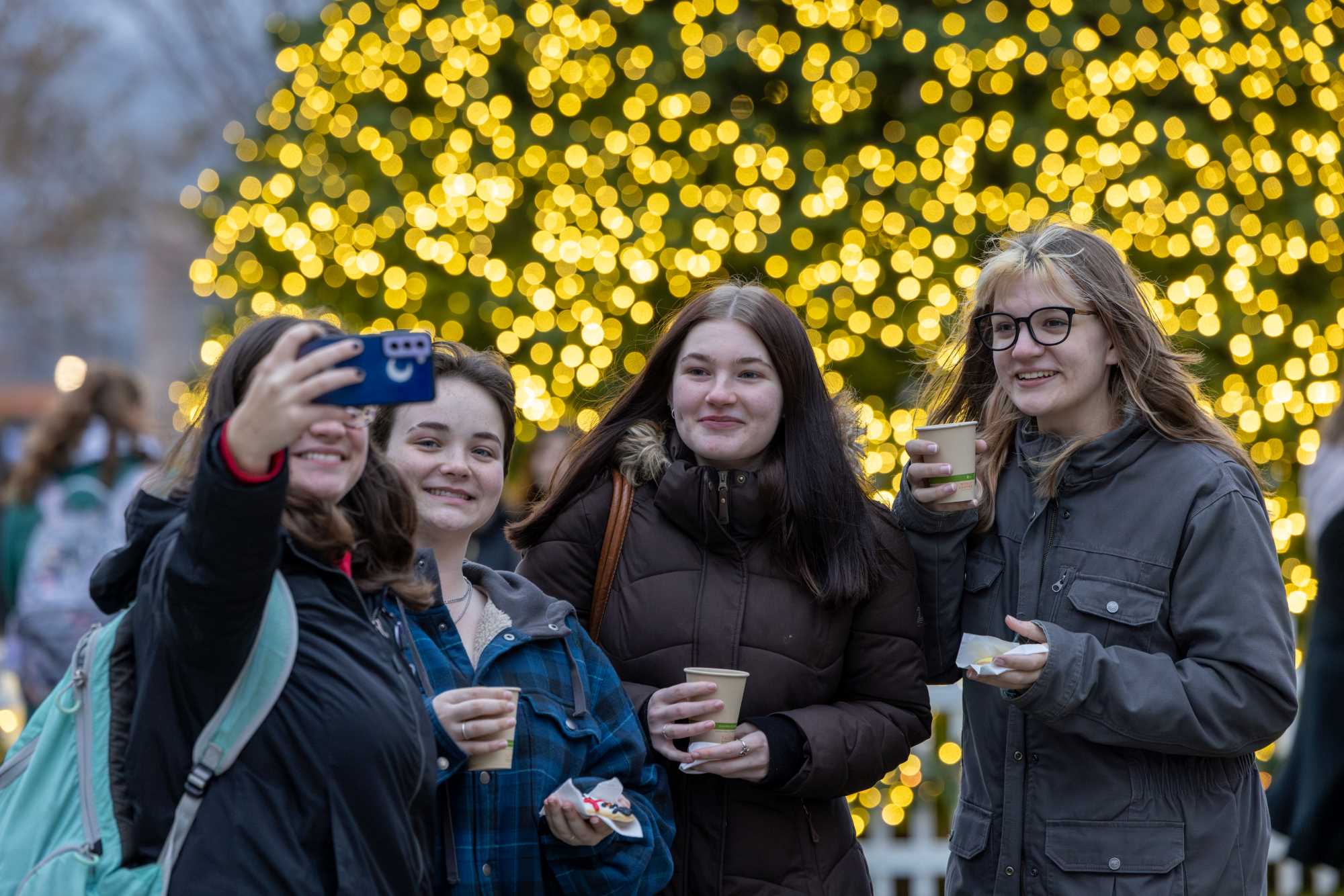 A group of students in front of the Campus Holiday Tree.