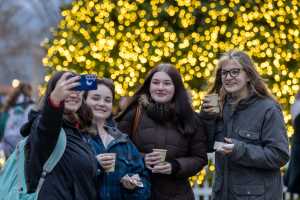 A group of students in front of the Campus Holiday Tree.