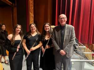 Chancellor Beeby posing for picture with 3 flutists at UWL band concert Spring 2026.