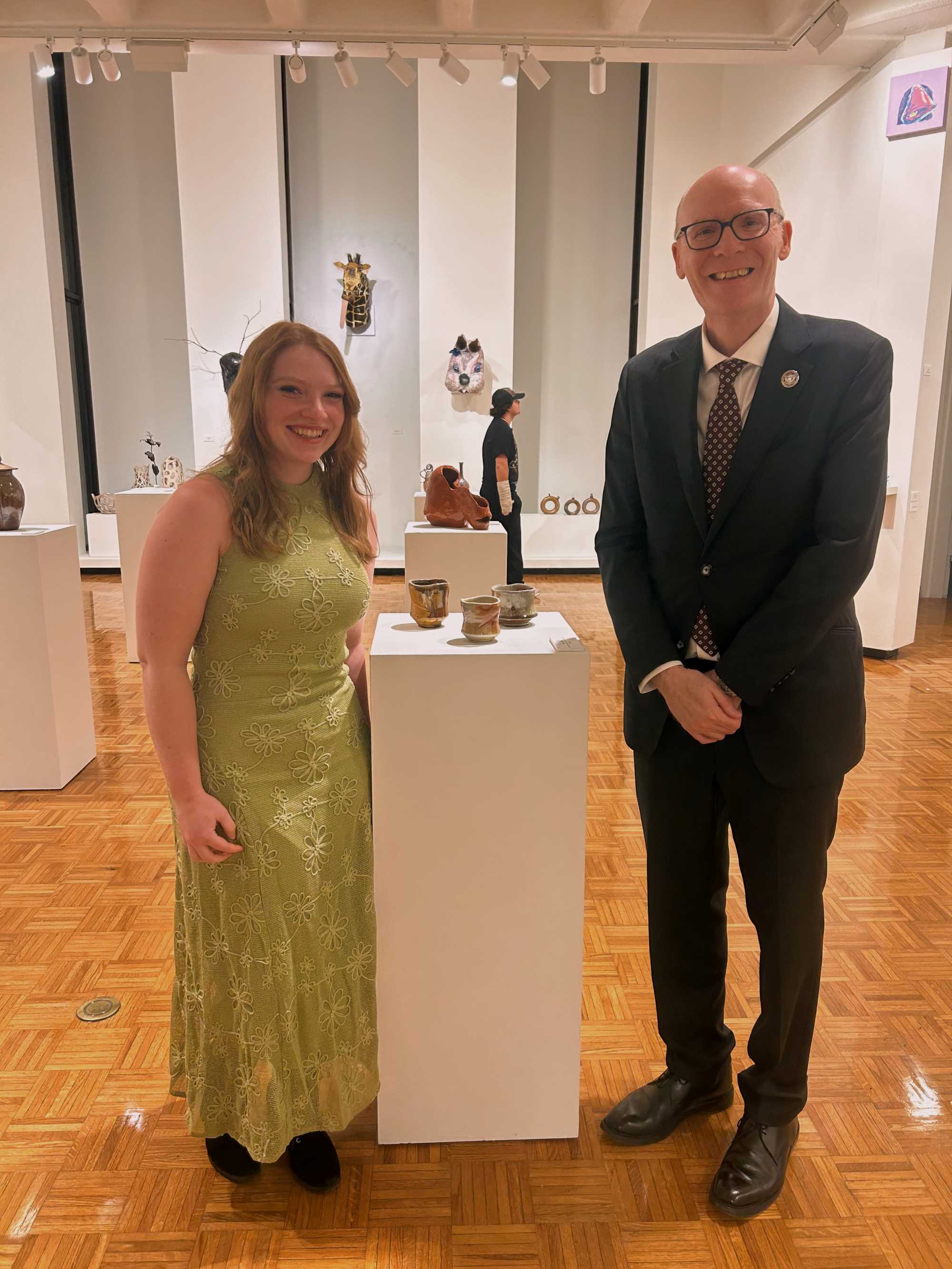 Chancellor Beeby standing with student by her ceramic display at the All-Student Juried Art Exhibition Spring 2026.