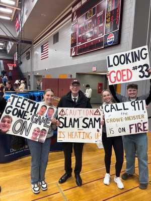Chancellor Beeby with 3 students holding signs at UWL Men's playoff basketball game Spring 2026.