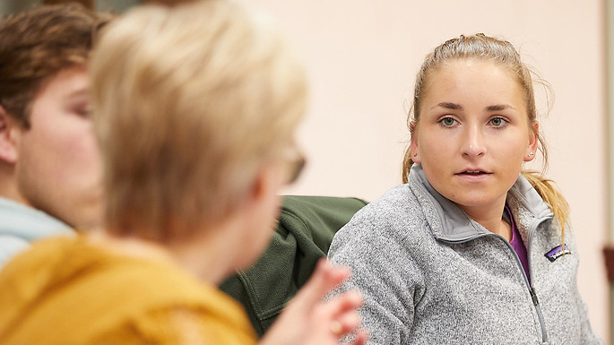 Image of a female student listening to someone speak