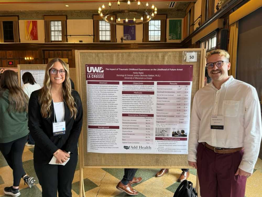 Two students stand in front of a research poster