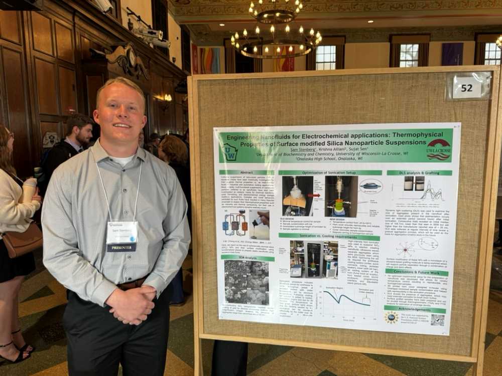 A student stands near his research poster
