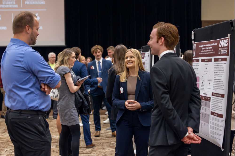 Two students present their graduate research poster to an onlooker at the 2025 Research & Creativity Symposium.
